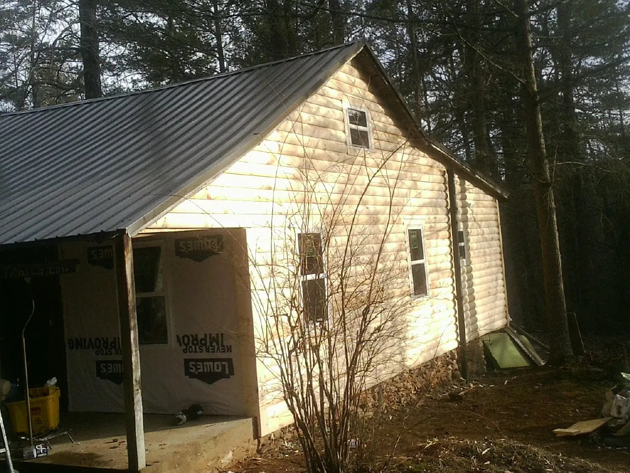 Log siding gable end under a dark metal roof edge in Hanska