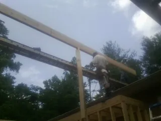 Carpenter setting a ridge beam over a new addition frame — Ice Dam Removal by Roofing Brothers in Hanska