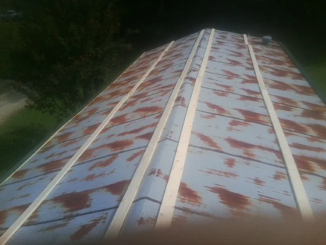 Rusted metal roof panels with new wood purlins before replacement — Storm Damage Roof Repair in Hanska by Roofing Brothers