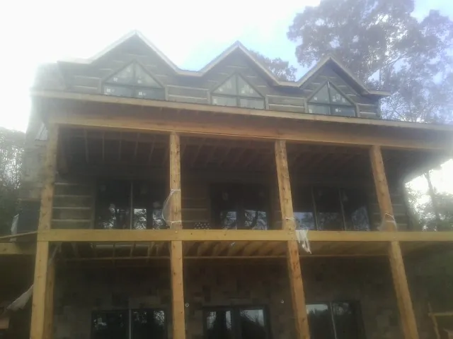 Dormers and porch framing on a large log home under construction — Roof Coating work by our crew in Hanska
