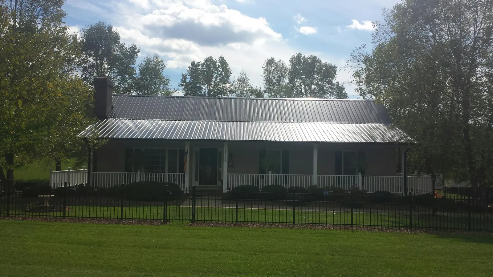 Gray metal roof on a brick ranch with a full width front porch — Gutter Guard Installation work by our crew in Hanska